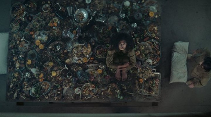 Escena de la película El Hoyo en la que aparece una mujer sentada sobre comida