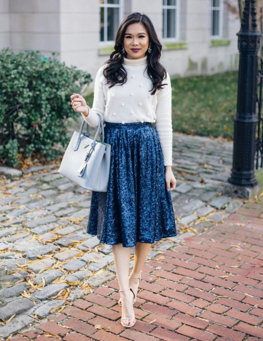 Pantone elige el classic blue como el color del 2020; mujer con falda azul clásico de terciopelo, blusa blanca y bolsa grande de mano