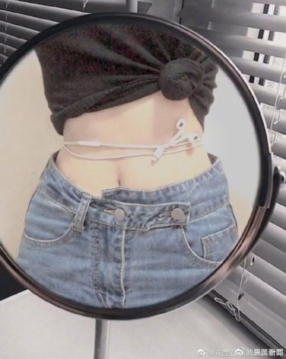 Chica midiendo el tamaño de su cintura con el cordón de los audífonos