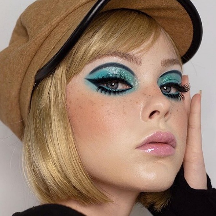 chica rubia con sombra color aqua, delineado de cat-eye negro, gloss transparente, tipo sesentero