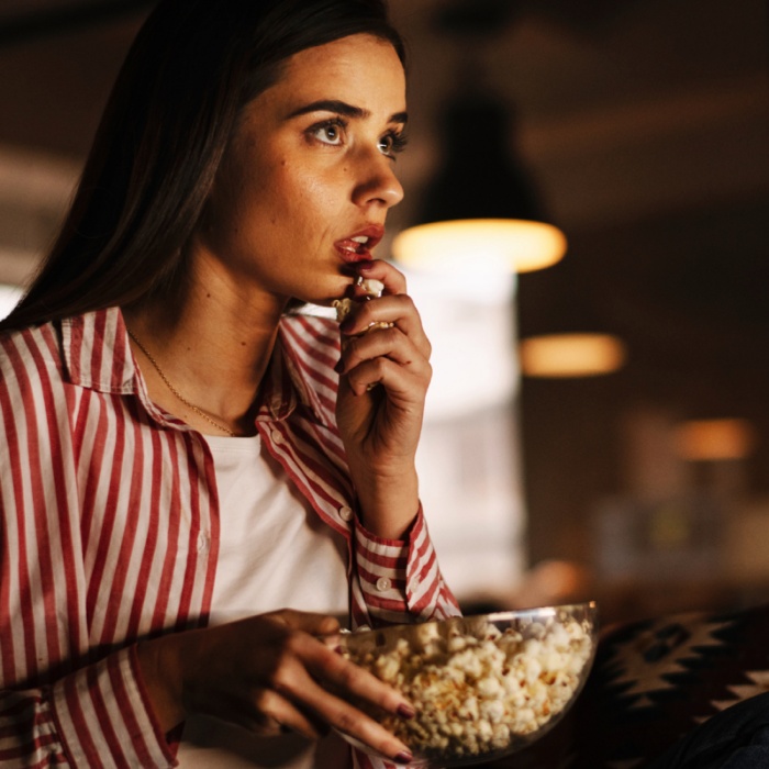 chica viendo películas de terror comiendo palomitas