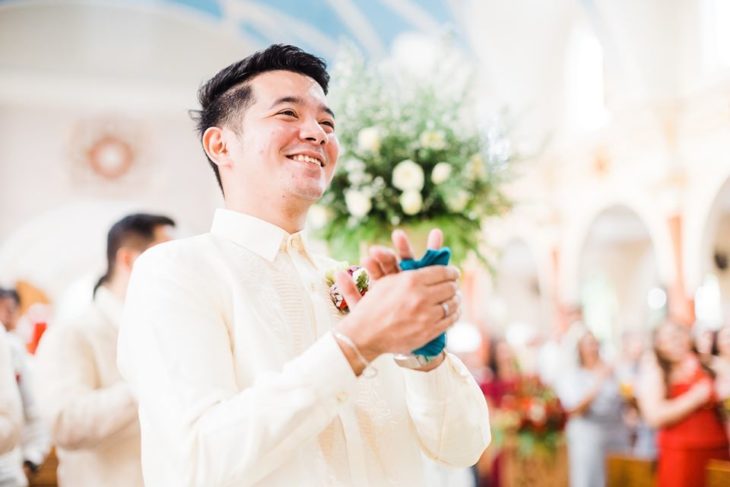 Chico vestido de novio mientras observa a su esposa acercándose al altar