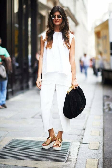 Chica con un look total white y sandalias doradas