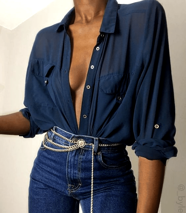 chica morena con camisa azul de vestir, jeans a la cintura ajustados con cinturón metálico dorado