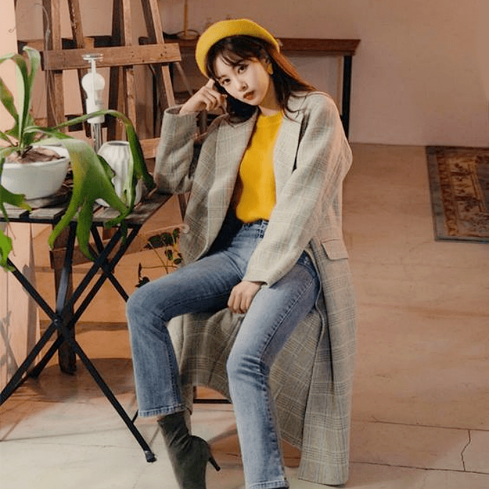 mujer de cabello castaño con un beret amarillo, suéter tejido amarillo, abrigo gris, jeans, botines gris oscuro