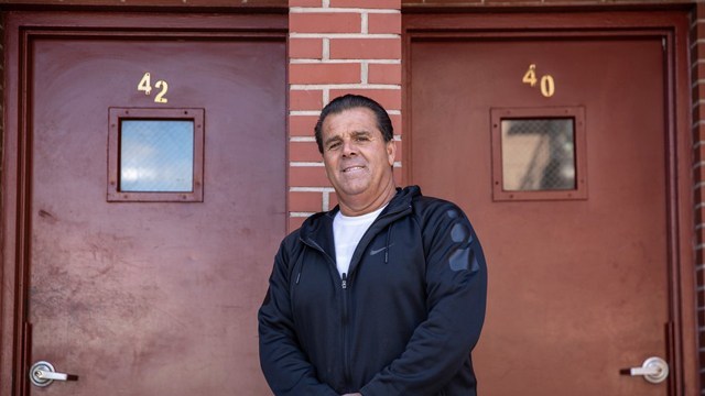 Mario Salerno posando para una foto frente a las puertas de su edificio 