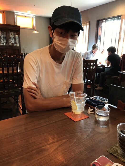 hombre japonés sentado en un restaurante con una bebida en la mesa