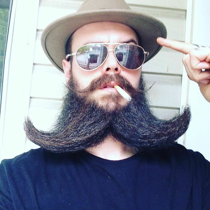 Hombres usando doble bigote en el rostro mientras lo peinan con gracia