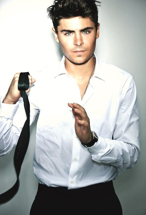 Zac Efron usando camisa de vestir blanca y con la corbata en la mano