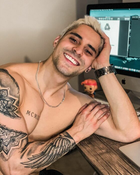 Chico posando para una foto mientras está apoyando su mano en un escritorio