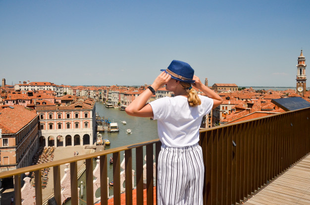 Chica parada en la orilla de un puente mirando el mar de Italia
