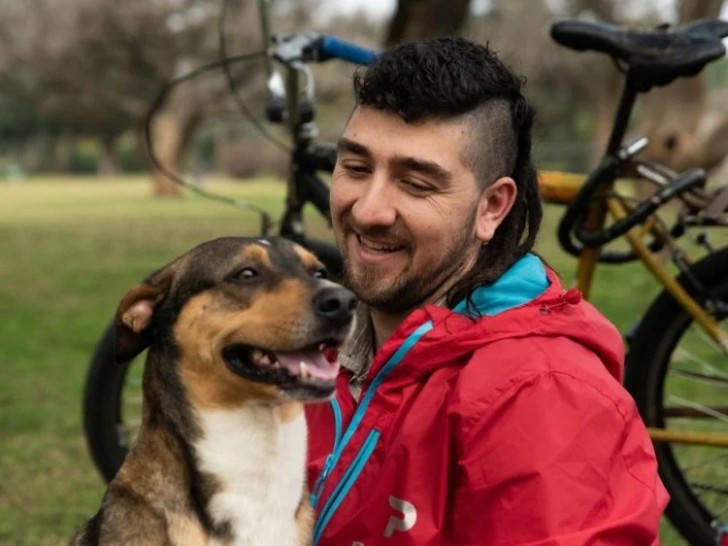 Joven y su perrito posando juntos en una bicicleta