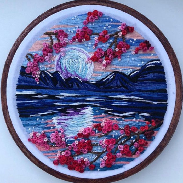 Bordado en aro hecho a mano de una noche despejada, el reflejo del cielo en el agua y flores de cerezo