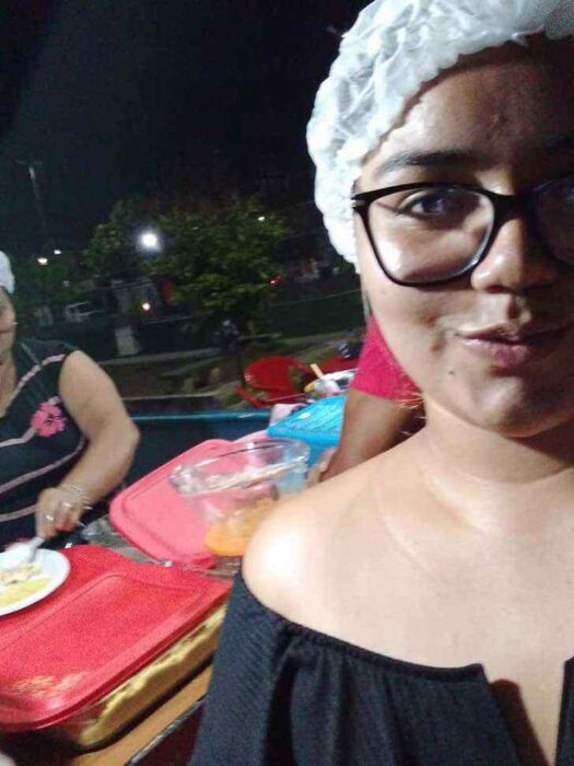 Chica vendiendo comida en un puesto que está en la esquina de una calle