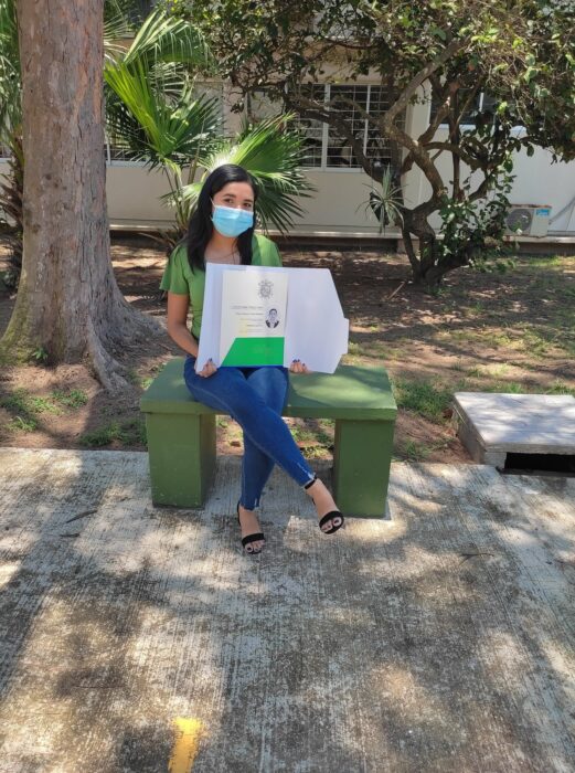 Evelin Hipólito sentada en una banca; Chica posa orgullosa con su título universitario en el banco donde vendía dulces