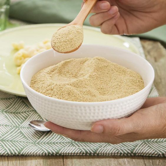 Mano sosteniendo un tazón con levadura nutricional