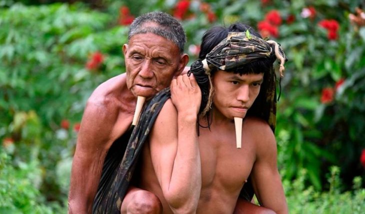 Nativo brasileño cargando a su padre en la espalda