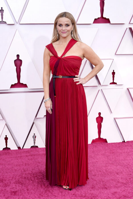 Reese Witherspoon en la alfombra roja de los Oscar usando un vestido de color rojo quemado