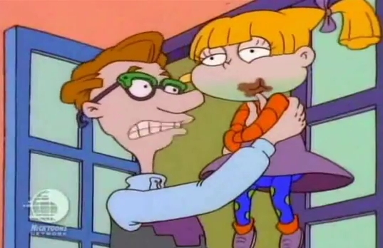 Angelica Pickles mientras está comiendo chocolate y su papá Drew la sostiene en brazos