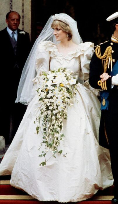 Diana Spencer el día de su boda luciendo un vestido blanco de encaje con un ramo de novia con flores blancas