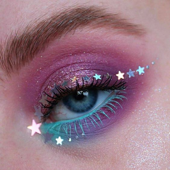 Maquillaje de ojos rosa con morado y azul con estrellitas