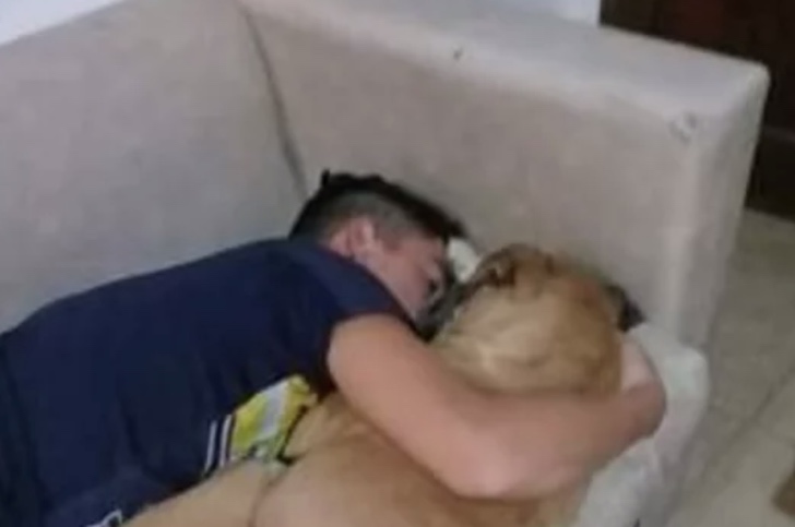 Chico abrazando a su perrita sobre un sofá