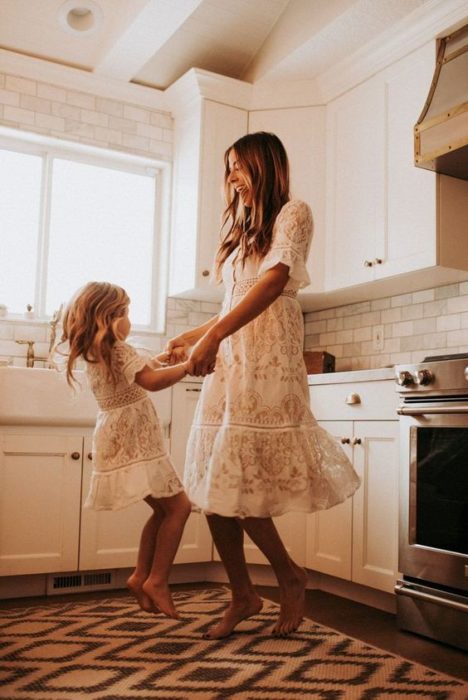 Madre e hija bailando en la cocina 