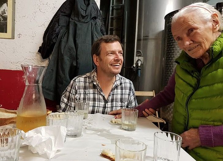 Hombre y su madre con alzheimer sentados en la cocina disfrutando de la comida 