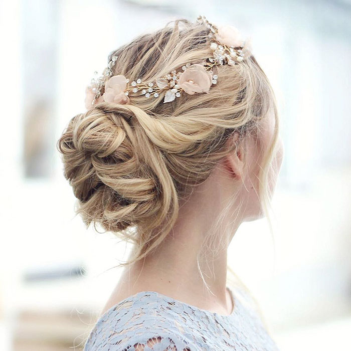 Mujer rubia con recogido suelto con flores rosas