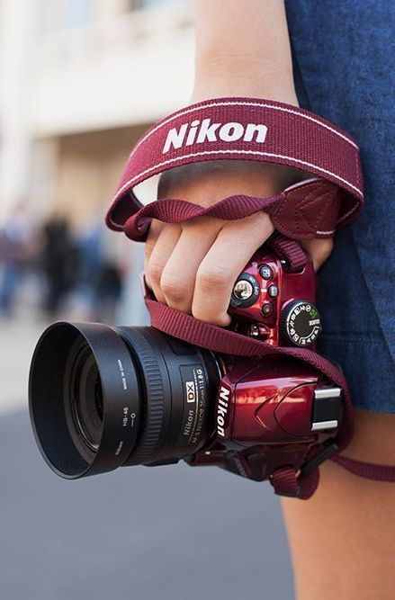 Chica con cámara Nikon y un listón color vino