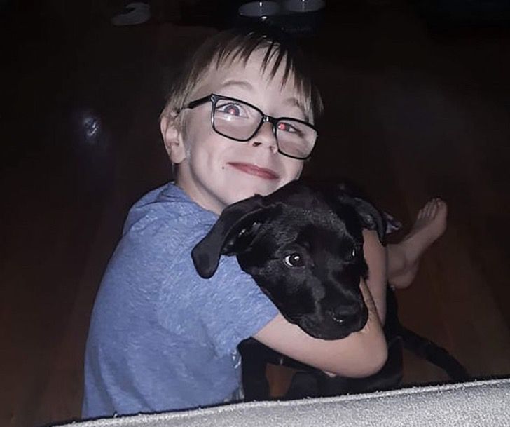 Niño jugando con su cachorro labrador de color negro 