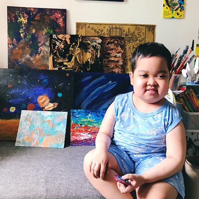 Aeden pio posando con algunas de las pinturas que ha hecho