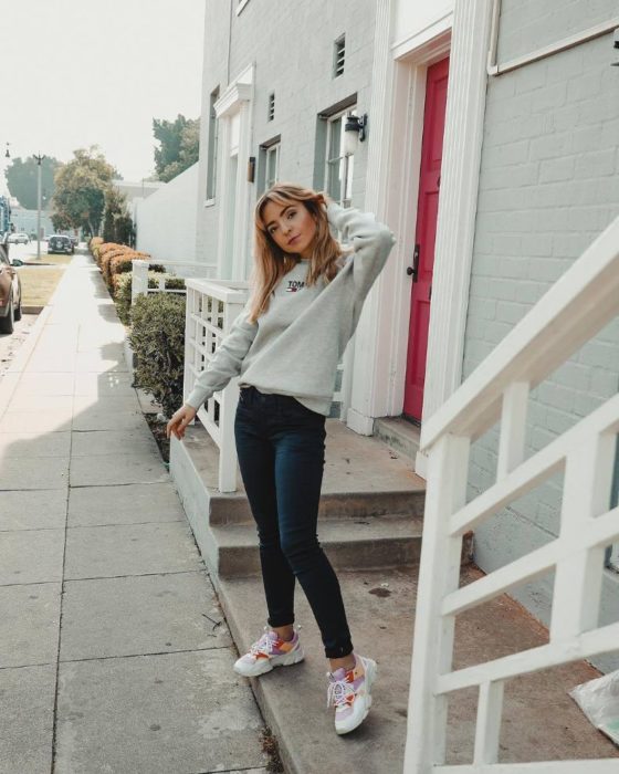 Chica usando unos skinny jeans con suéter blanco y tenis