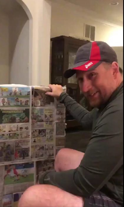 imagen con un nombre sosteniendo un cuadro envuelto con papel periódico