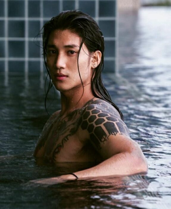 Paing Takhon sin camiseta en una piscina con el cabello mojado mirando a la cámara 