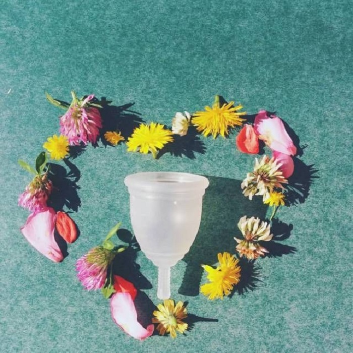 Copa menstrual rodeada por un corazón de flores