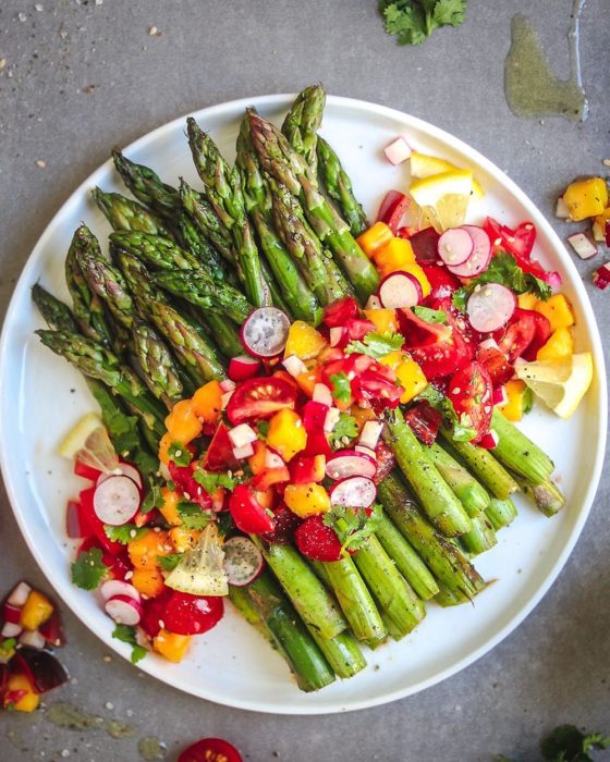 Plato de comida alcalina, espárragos con rábanos, y verduras varias, además de aceite de oliva