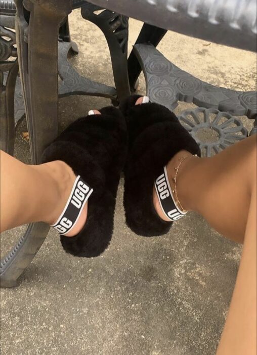 pies de una chica usando pantuflas furry UGG en color negro