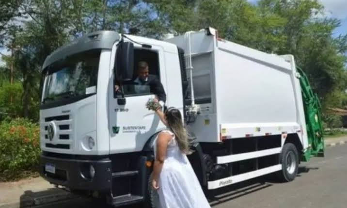 Pareja de novios tomados de la mano frente a un camión de basura; Recién casados toman sus fotos de boda en un camión de basura; él es recolector