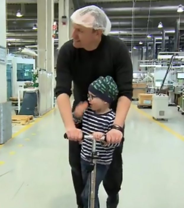 Padre e hijo jugando en un patín dentro de una fábrica