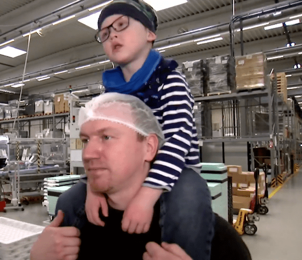 Padre cargando a su hijo en hombros dentro de una fábrica