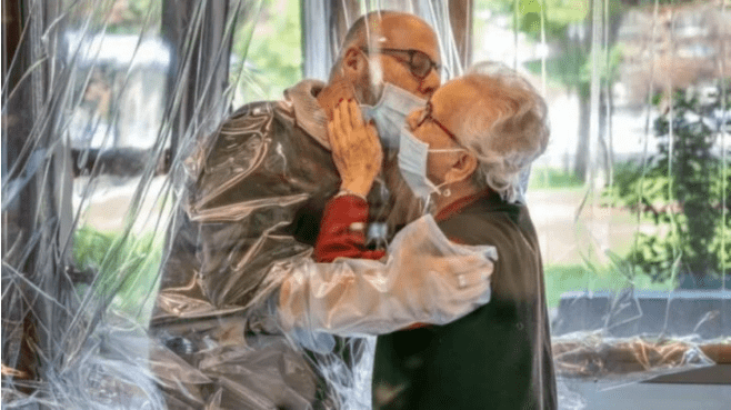 Anciana abraza a su hijo mediante plástico de seguridad en sala de abrazos