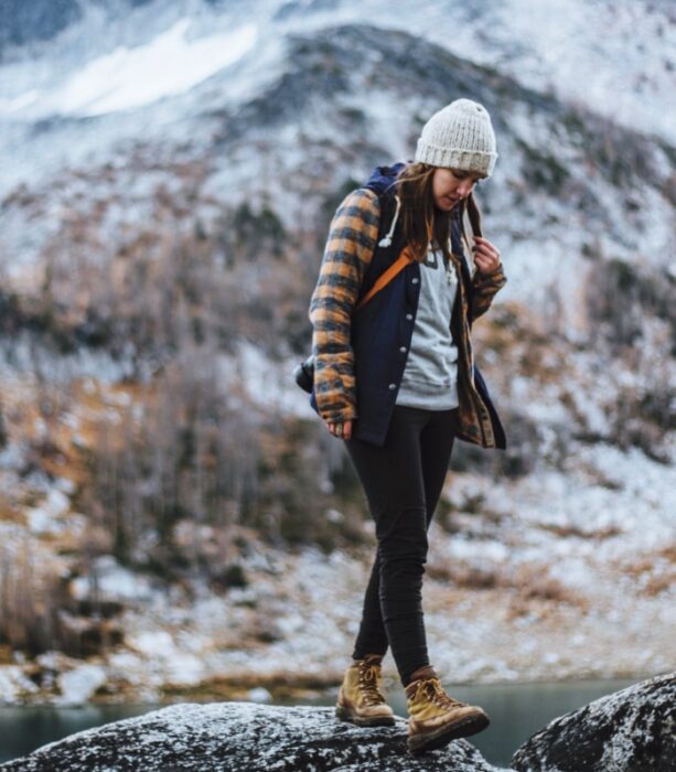 chica, mujer con cabello largo, usando gorro tejido, chamarra, jeans, botas de montaña, sudadera, suéter y chaqueta de cuero