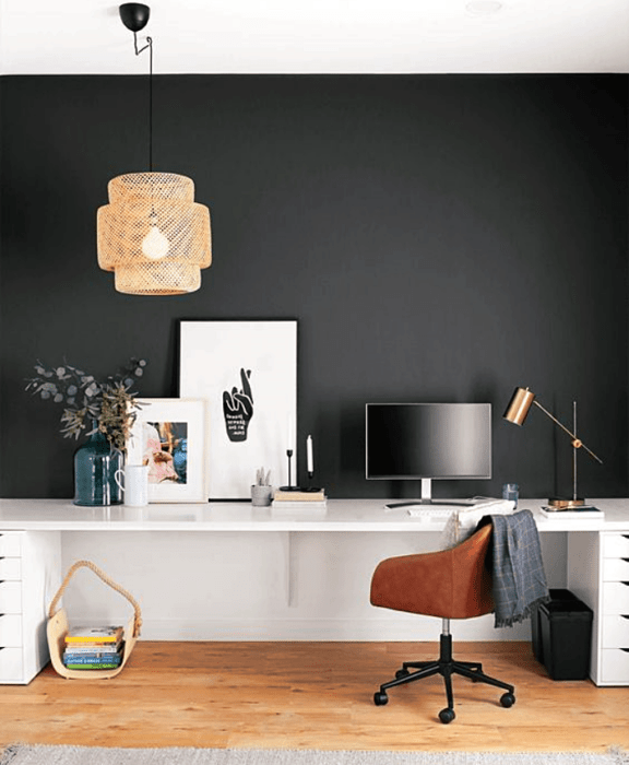 oficina con pared negra, escritorio blanco, silla café moderna y cuadros decorativos blancos, lámpara beige