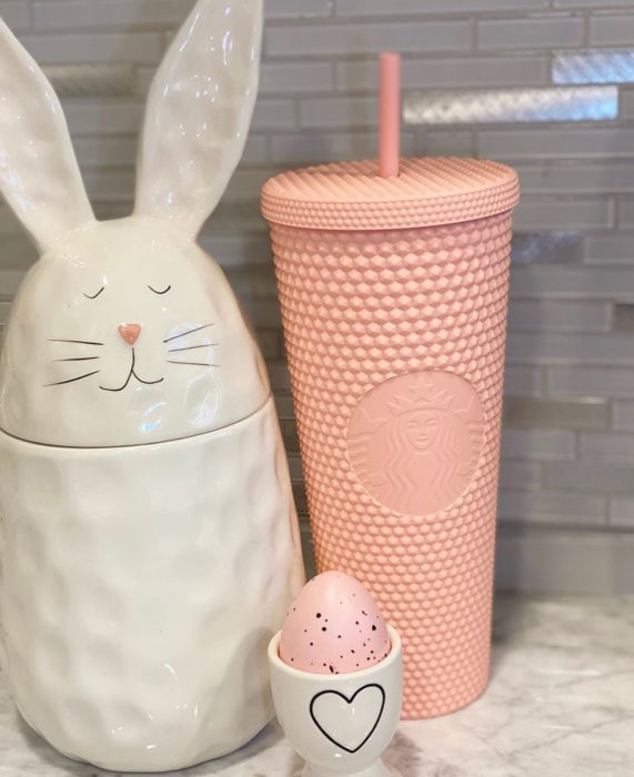 Vaso rosa pastel junto a un conejito galletero
