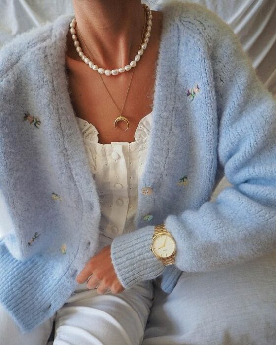 Chica con jeans claros, blusa blanca y suéter de punto con botones color azul