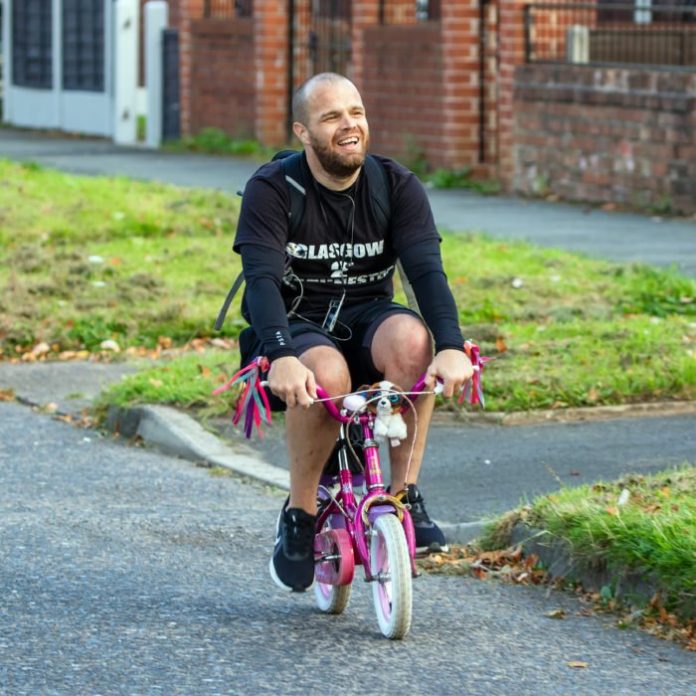 Hombre pedaleando en una bicicleta rosa