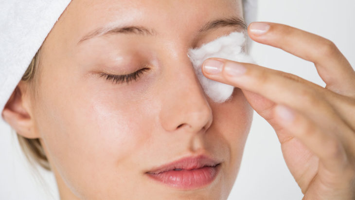 Mujer desmaquillándose los ojos con algodón