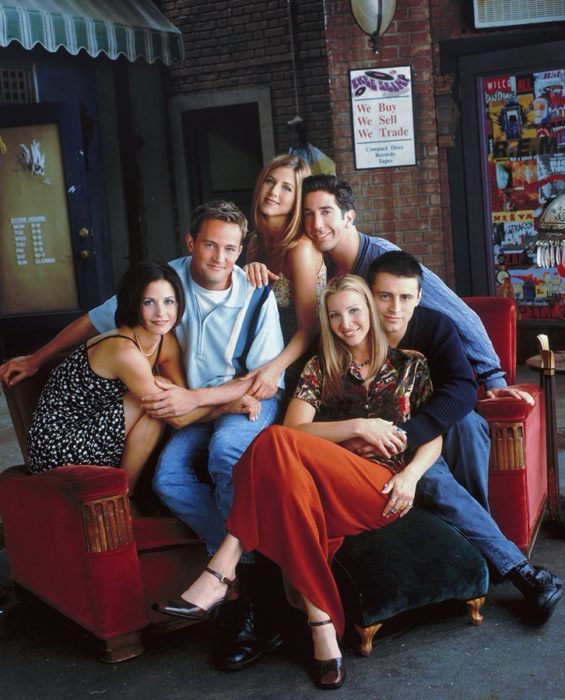 Elenco de Friends reunido en un sofá rojo para una foto grupal